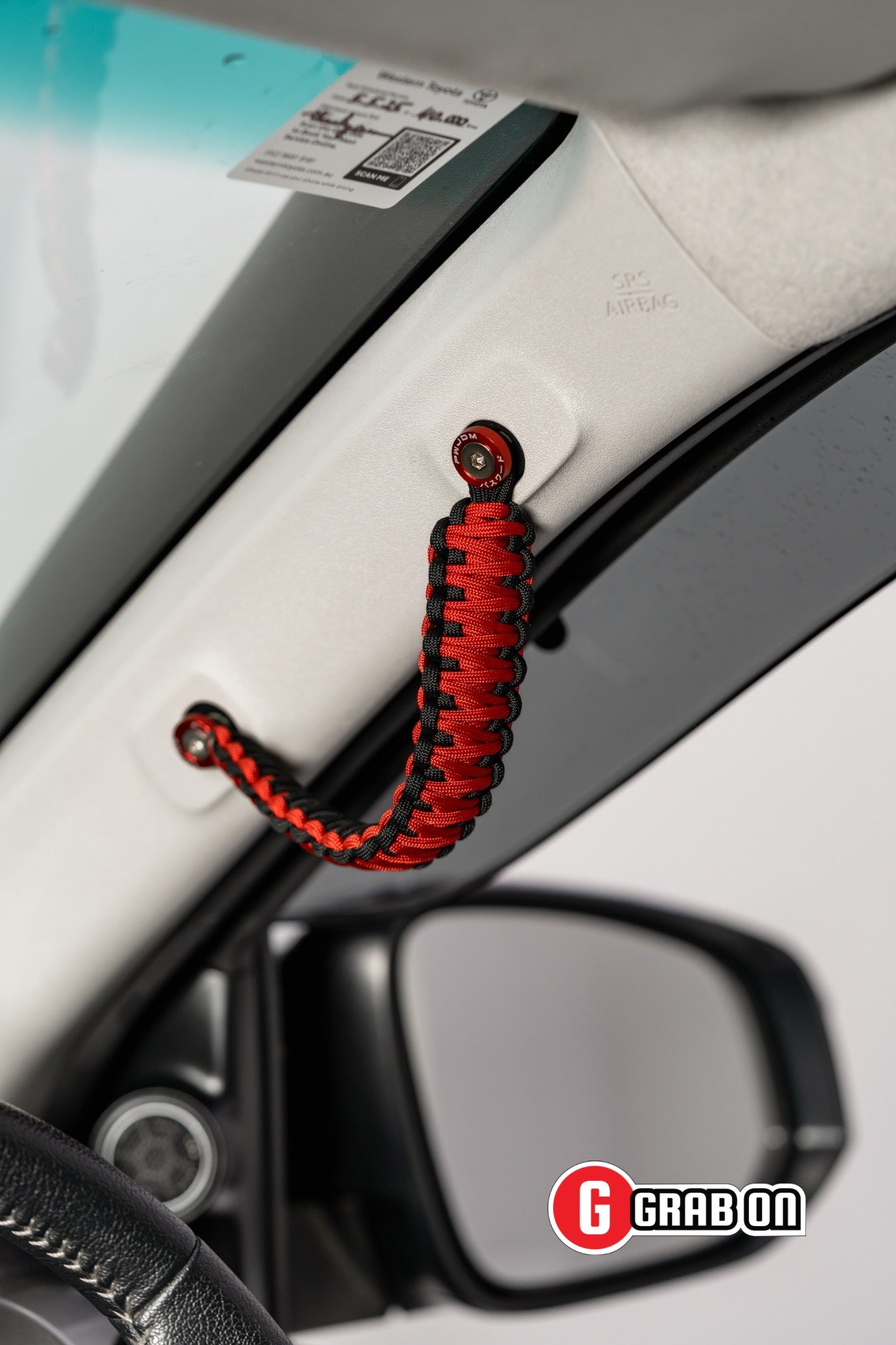 Red and black car handle cover attached to a car door with Grabon branding.