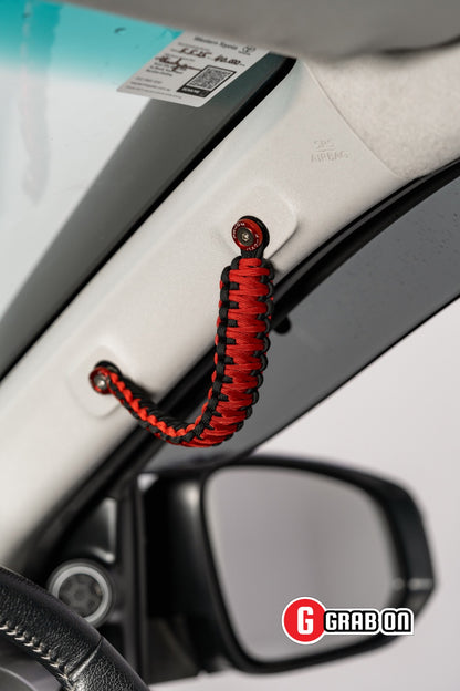 Red and black car handle cover attached to a car door with Grabon branding.