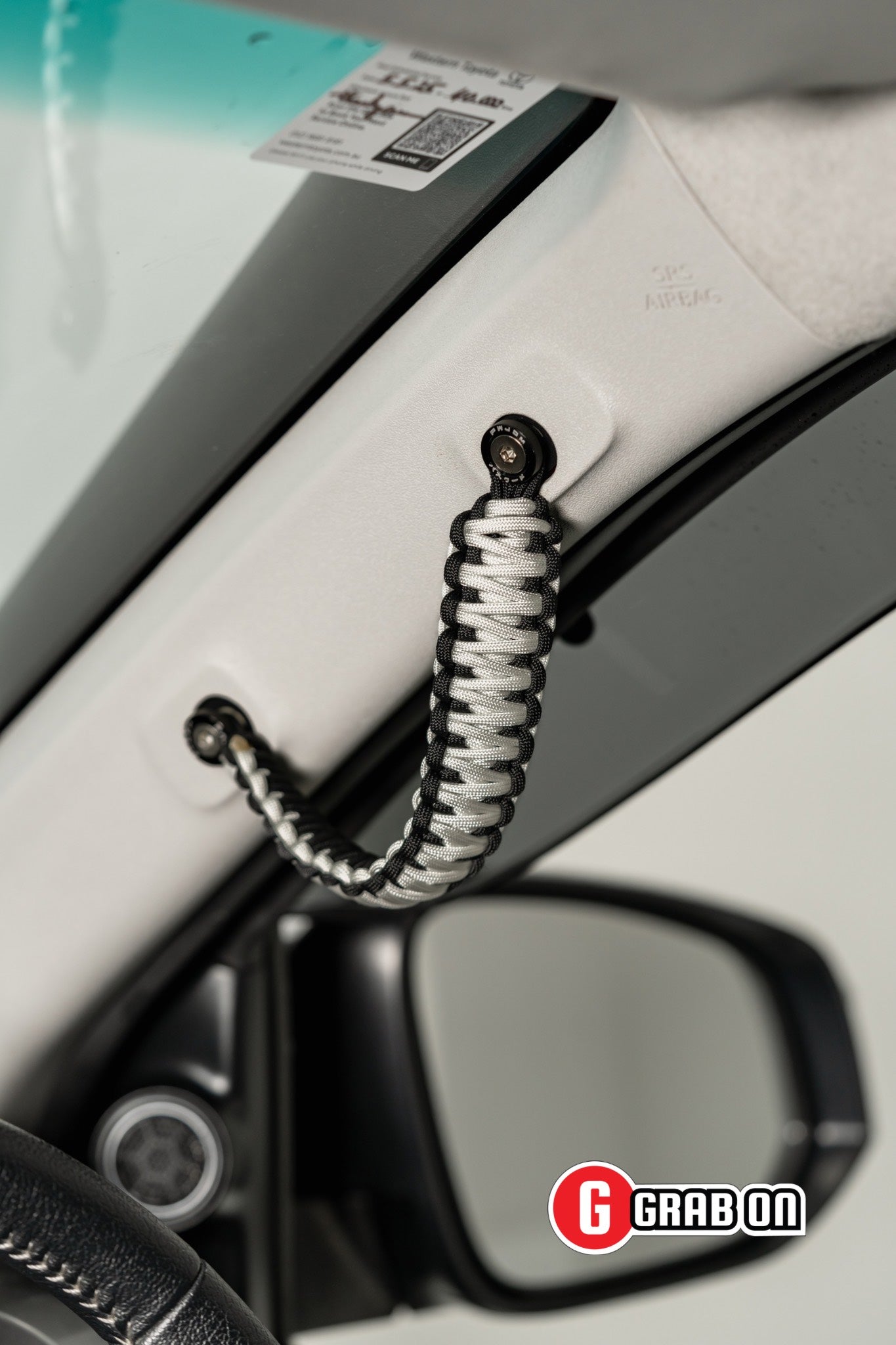 Car door handle with a coiled rope attached, brand 'Grabon' visible.